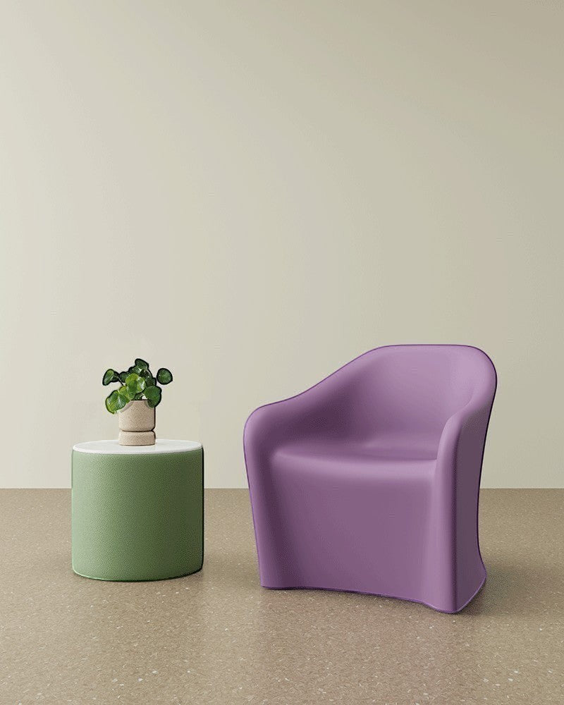 A Flo Lounge chair in Heather Purple colour is shown with an upholstered drum table with a solid surface table top